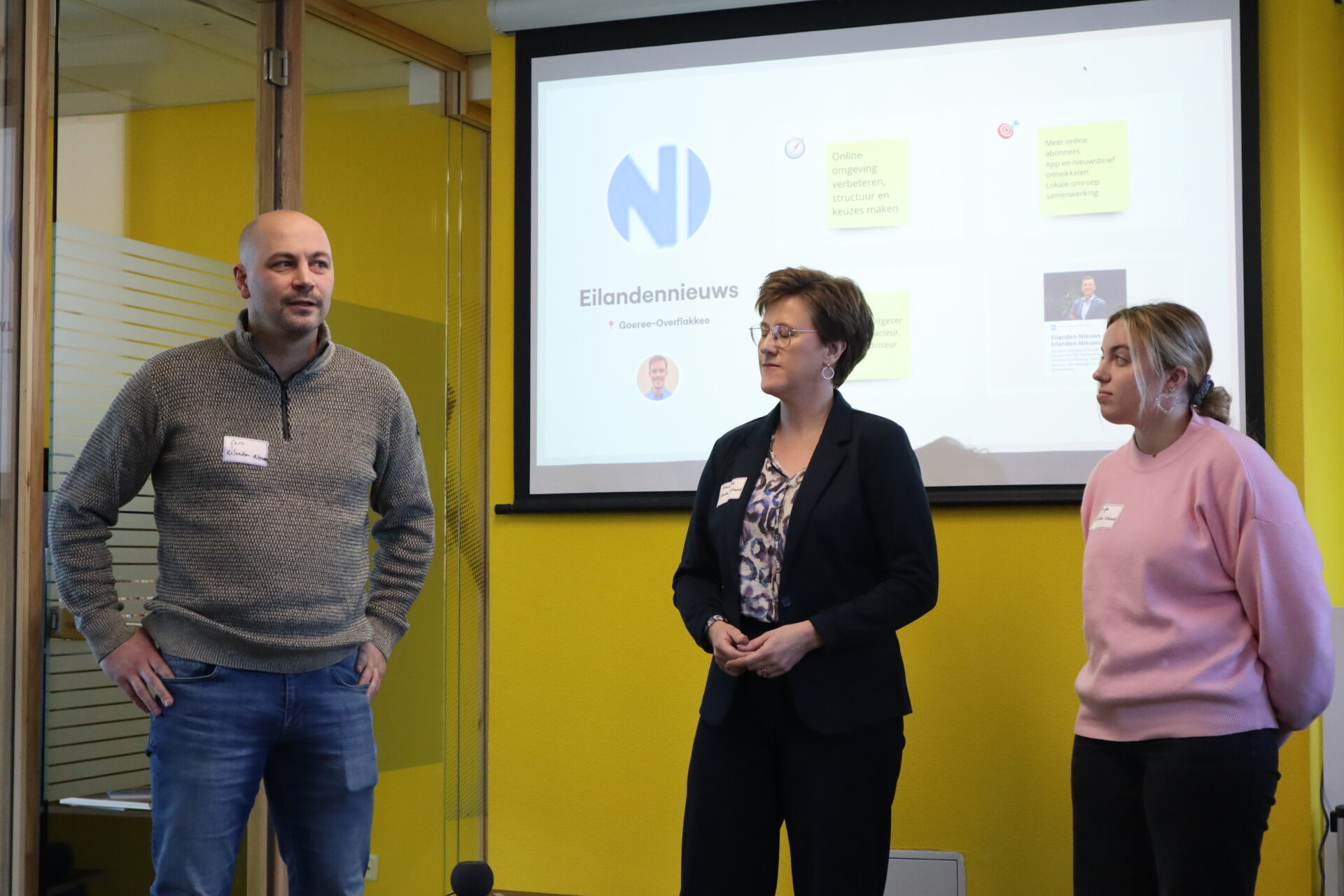 Drie mensen staan voor een presentatiescherm tijdens de bijeenkomst van het Coachingstraject in SIF Utrecht