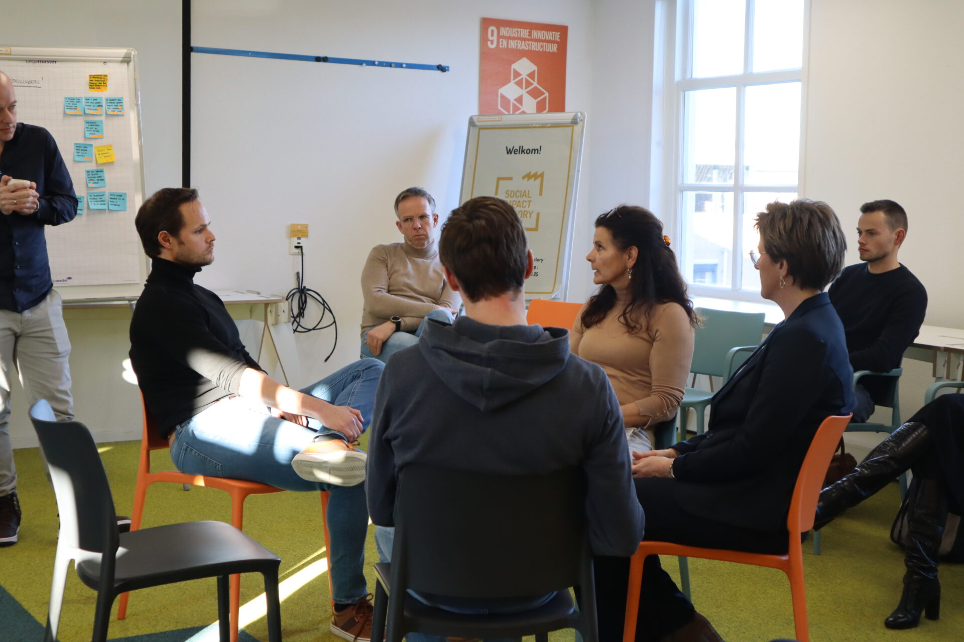 Groep mensen zit in een kring tijdens een fishbowl sessie van het coachingstraject.