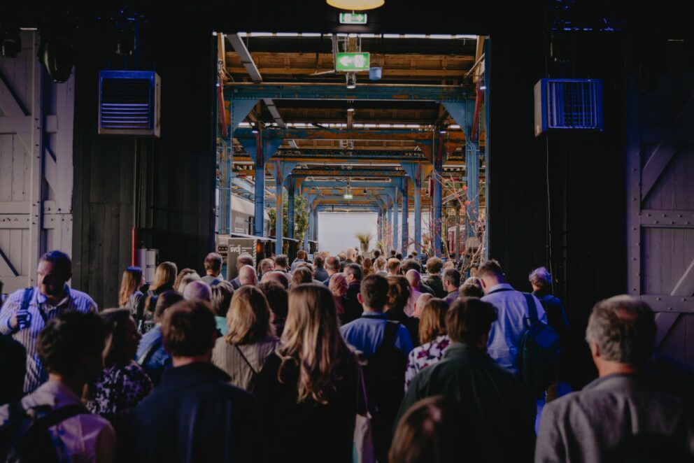 Grote groep mensen loopt tijdens event Media van Morgen door twee schuifdeuren.